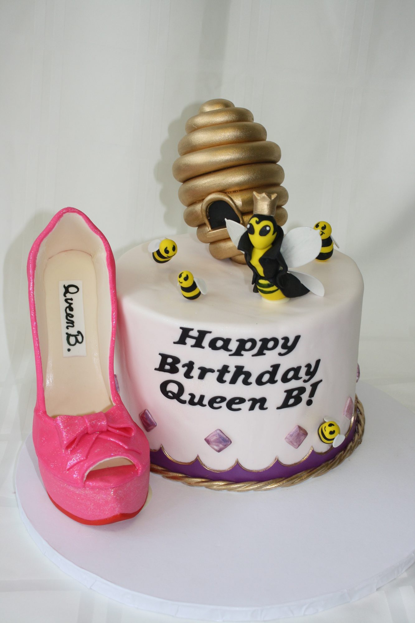 Queen bee birthday cake with a sugar beehive and pink stiletto